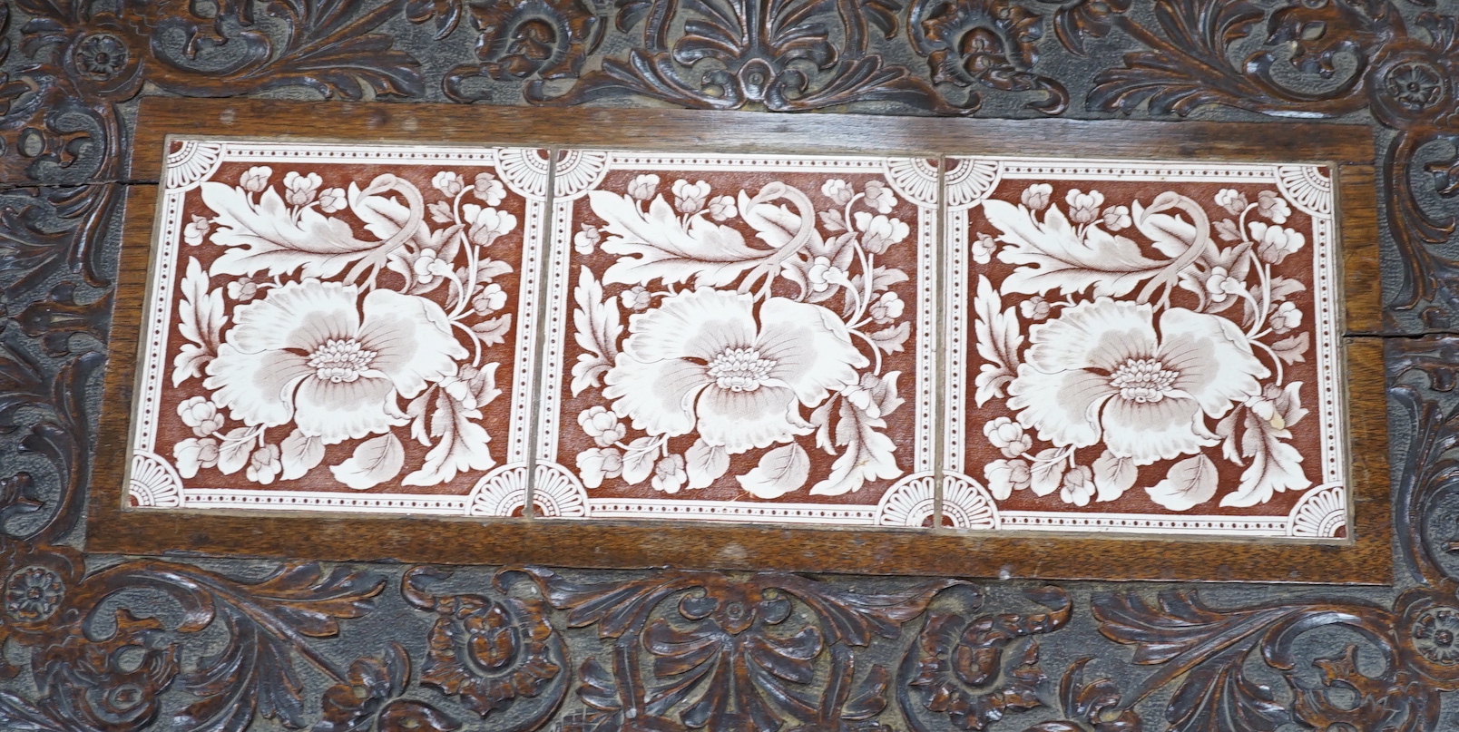 A Victorian carved oak stand inset with there floral tiles, 69cm wide